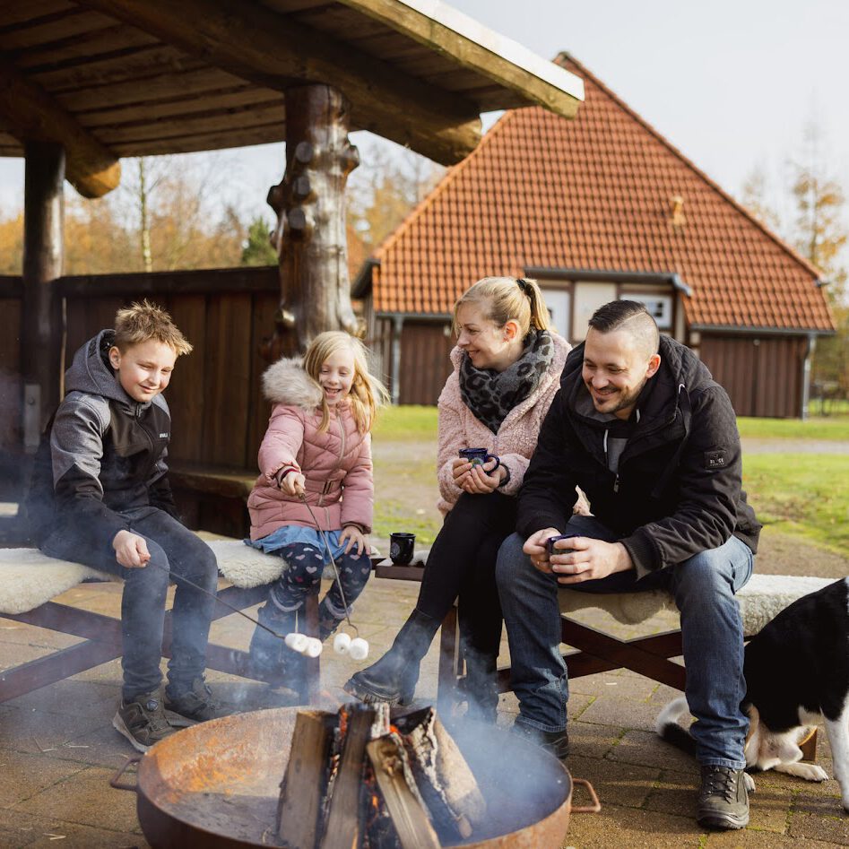 Familie an der Feuerschale vor der Grillhütte